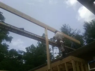 Carpenter setting a ridge beam over a new addition frame — Ice Dam Removal by Roofing Brothers in Ridge